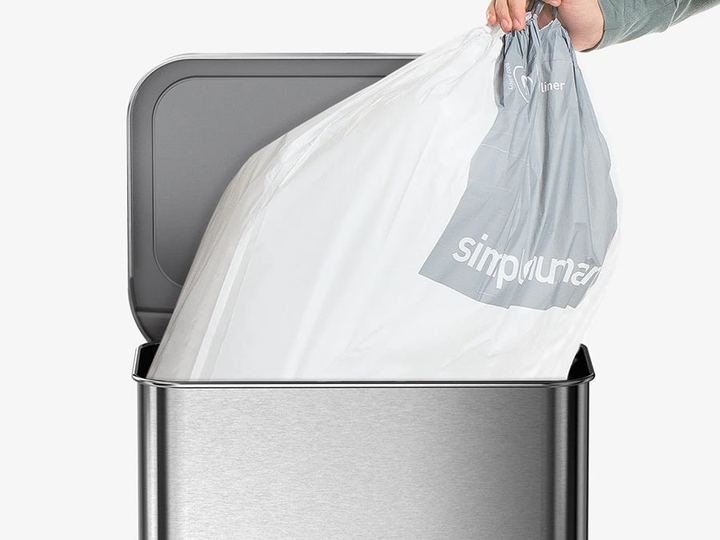 One hand lifting a full liner out of a bin