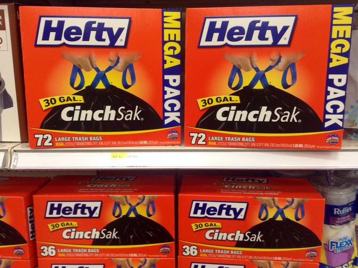 Hefty CinchSak boxes on a store shelf showing two hands tying